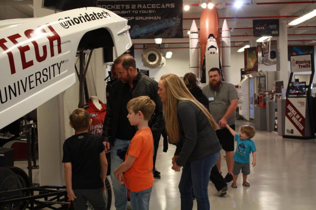 Groups of people are looking at the Florida Tech rockets at a space show.