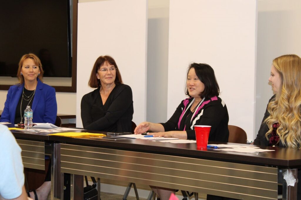 Four women sitting at a table looking at the presenter at the WIDSC Mentoring Panel.