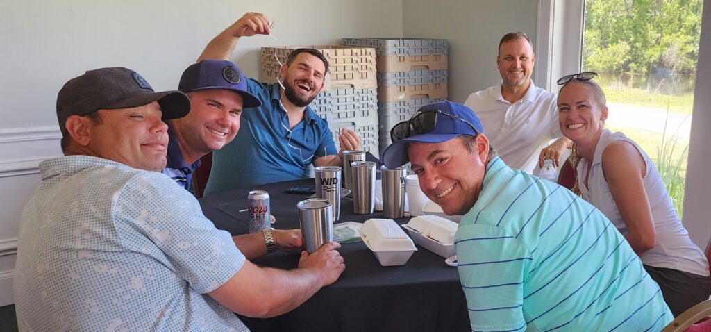 Six people sitting at a table at the 6th ANnual Sandbagger Invite.