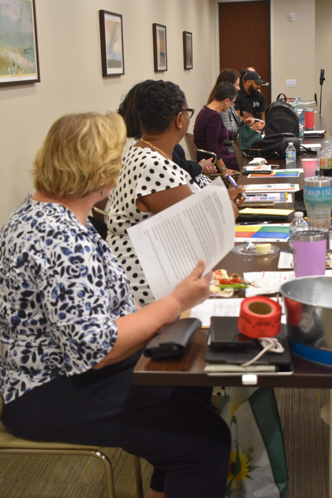 Women sit at the table looking down towards the end.