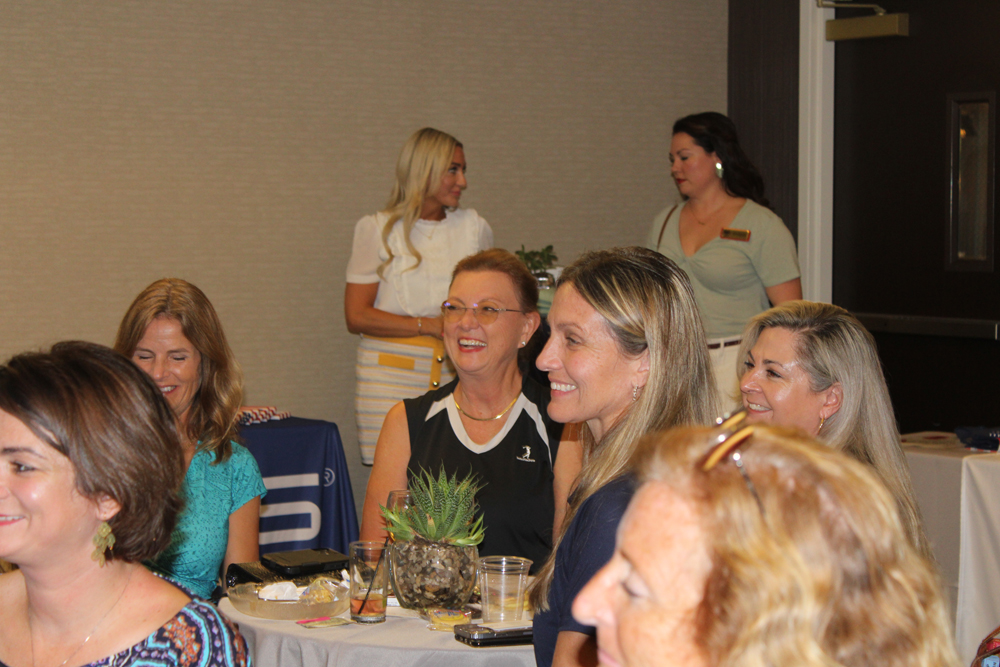 Women sitting at a table smiling looking at the presentation.