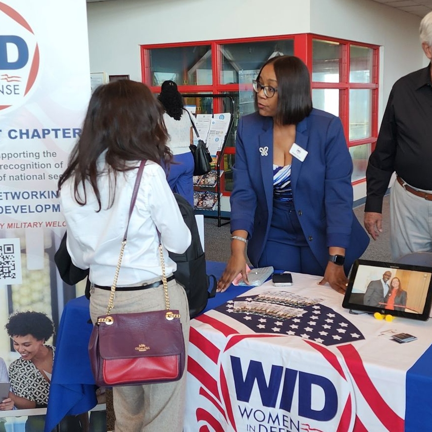 A member of WID Space Coast speaks with a prospective member at an event
