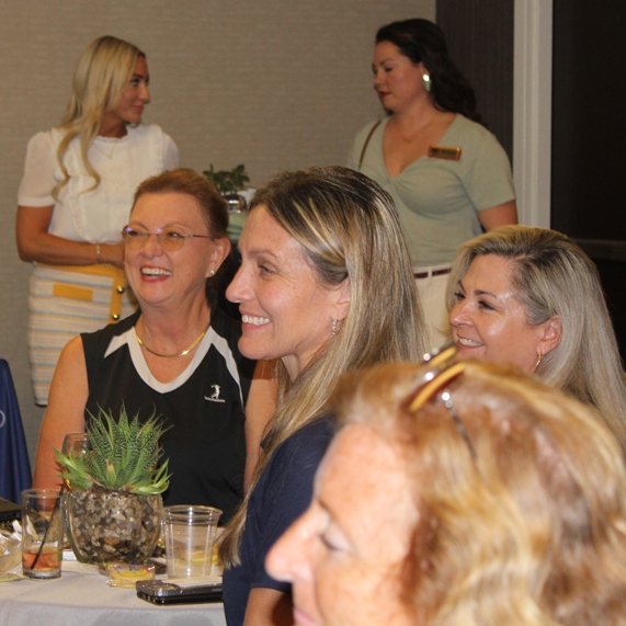 Women laugh at a WID Space Coast event.