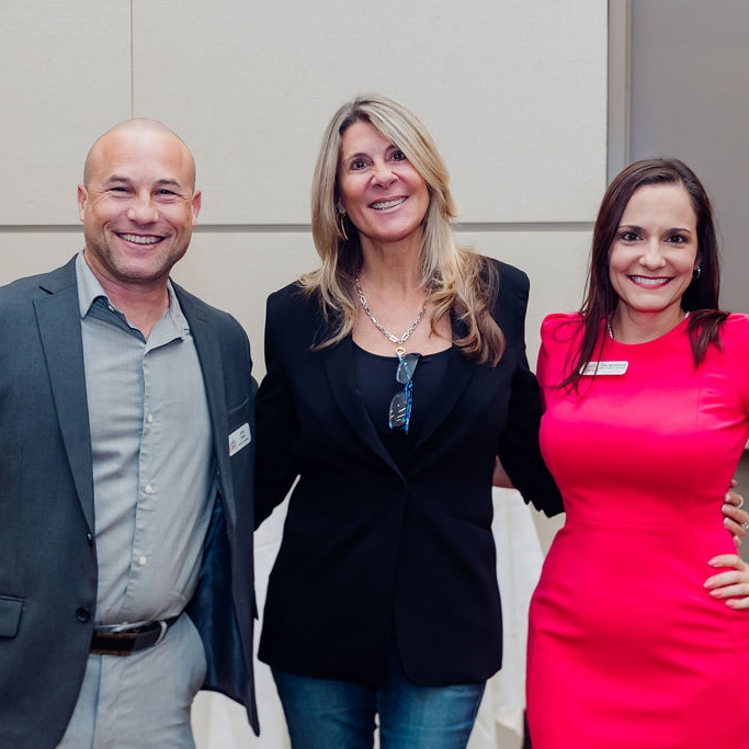 Three WID Space Coast members smile and pose at an event.
